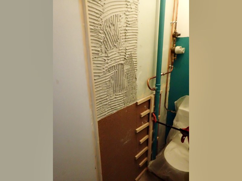 Collage de plaques de liège acoustique dans les toilettes pour réduire le bruit dans la chambre.