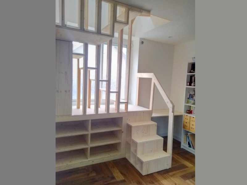 Des rangements sous l'escalier, un bureau à droite.